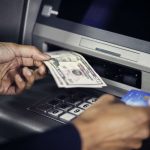 woman pulling money out of atm machine