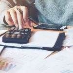 person at desk with calculator and papers