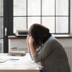 woman with headache sitting at table